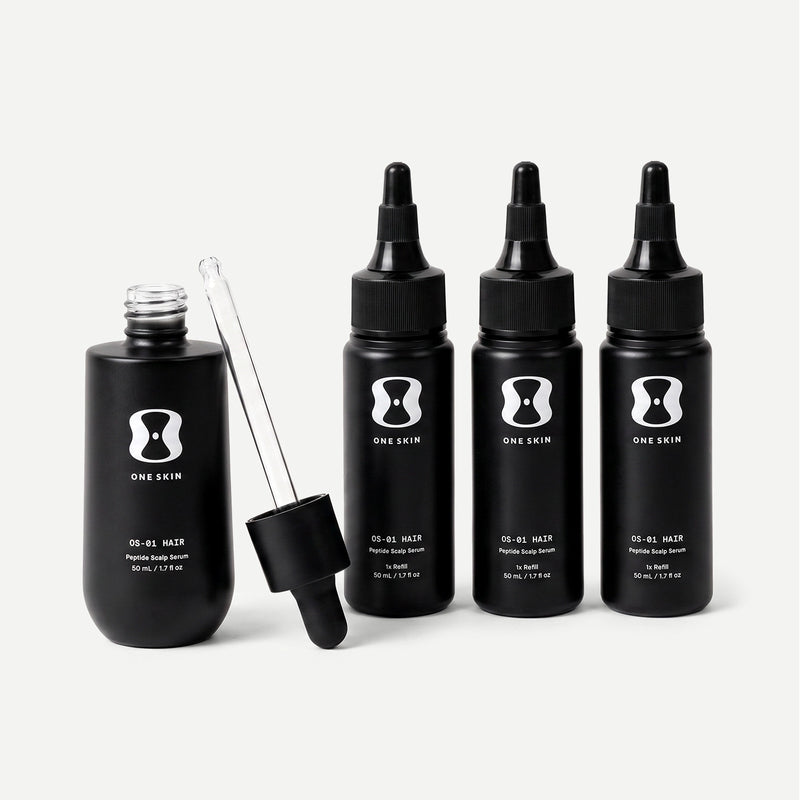 Set of black hair serum bottles with dropper and dermaroller on a light gray background contains descriptive text stating bottle size may vary, the 3 month supply will always come with 150mL of the OS-01 HAIR serum.