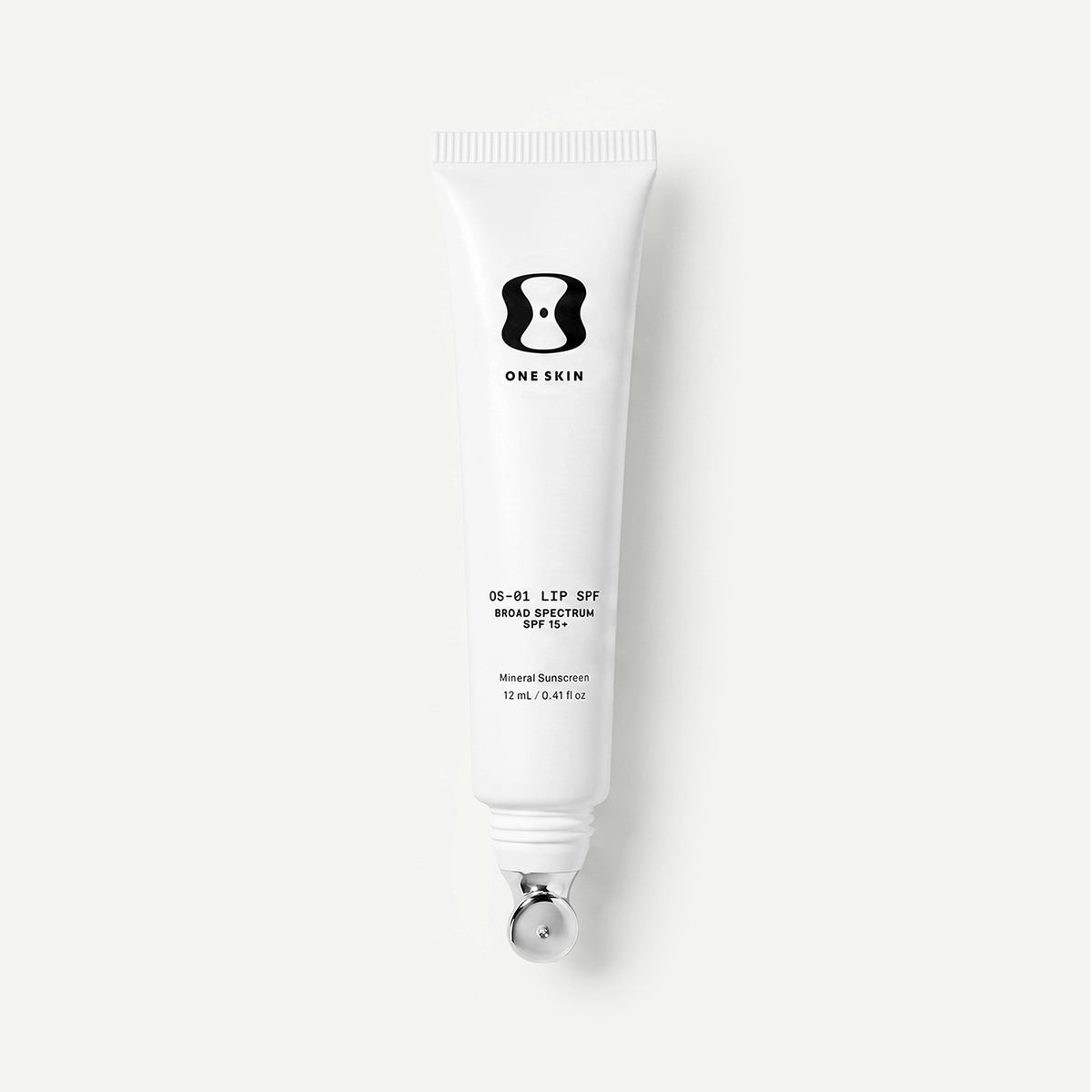 White tube of One Skin lip spf on a light beige background